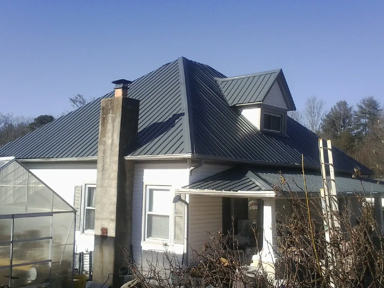 Dark blue standing seam metal roof on a white farmhouse with dormer — Slate & Tile Roof Repair by Roofing Brothers in New Ringgold