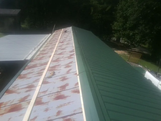 Old rusted panels beside newly installed green metal roofing — Wind Damage Roof Repair by Roofing Brothers in New Ringgold
