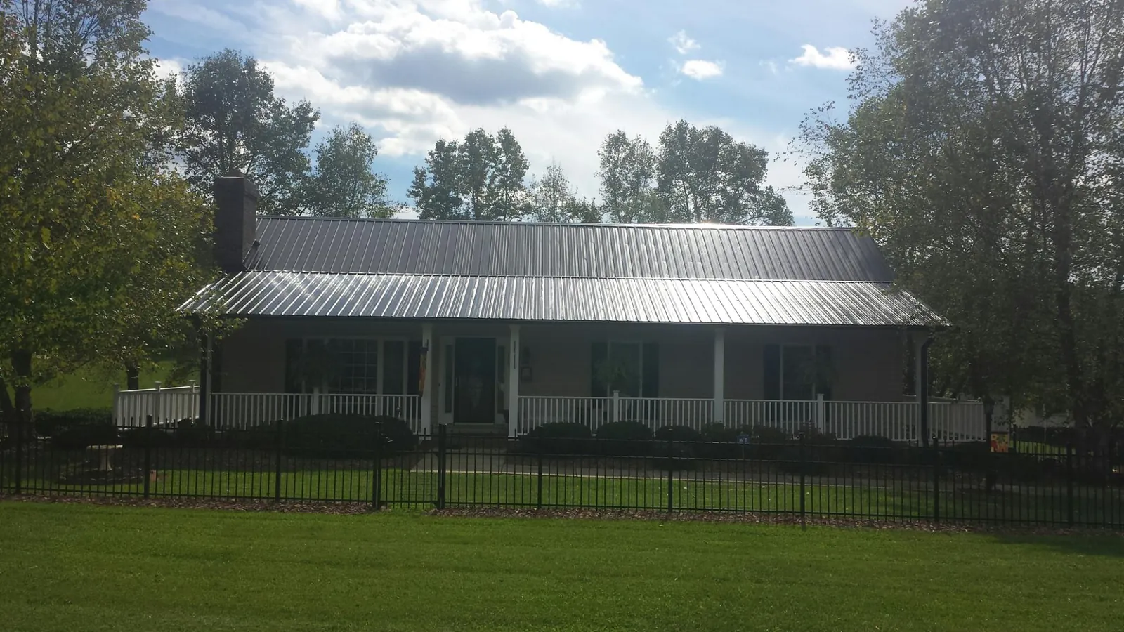 Gray metal roof on a brick ranch with a full width front porch — Gutter Guard Installation work by our crew in New Ringgold