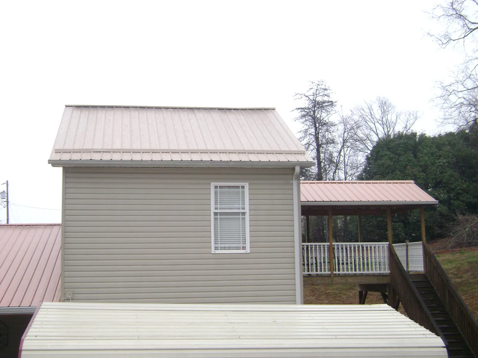 Tan metal roofs on a two story addition and attached porch, from a Roof Replacement job in New Ringgold